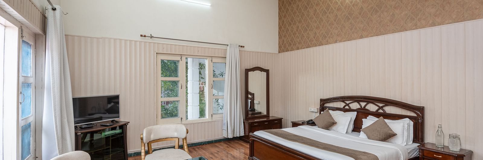 Spacious and bright guest room at DLS Tehri Club Resort with a king size bed and a seating area.